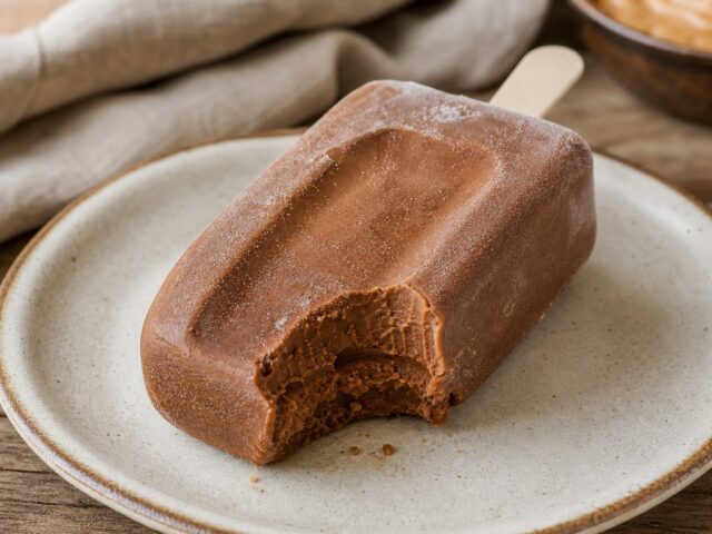 Frozen peanut butter protein fudge pop with a bite taken, showing the dense fudgy interior